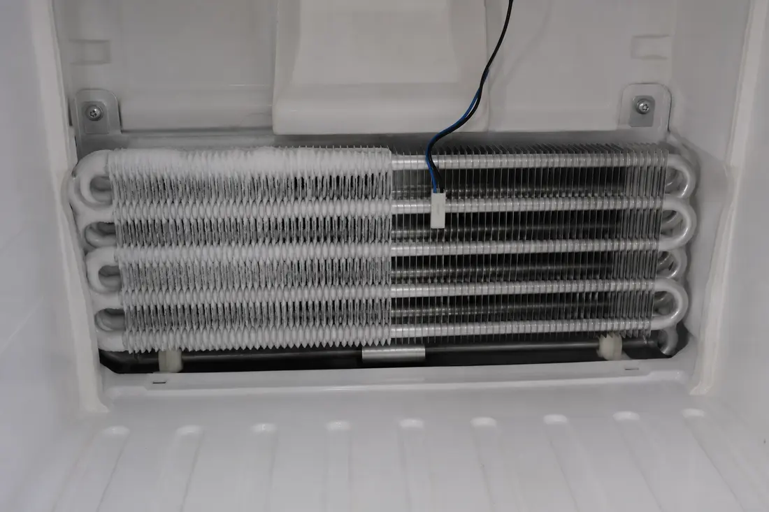 Freezer evaporator coil with patchy frost and a clipped temperature sensor
