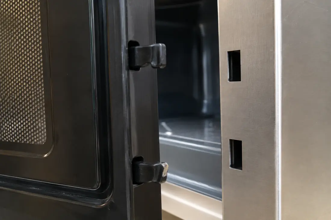 Microwave door latch hooks with a chipped lower hook aligned to the frame slots