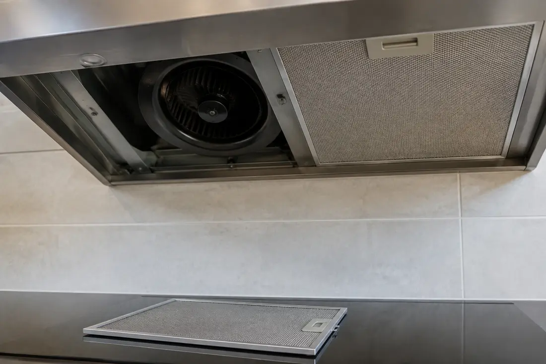 Stationary centrifugal blower visible behind a removed range hood filter