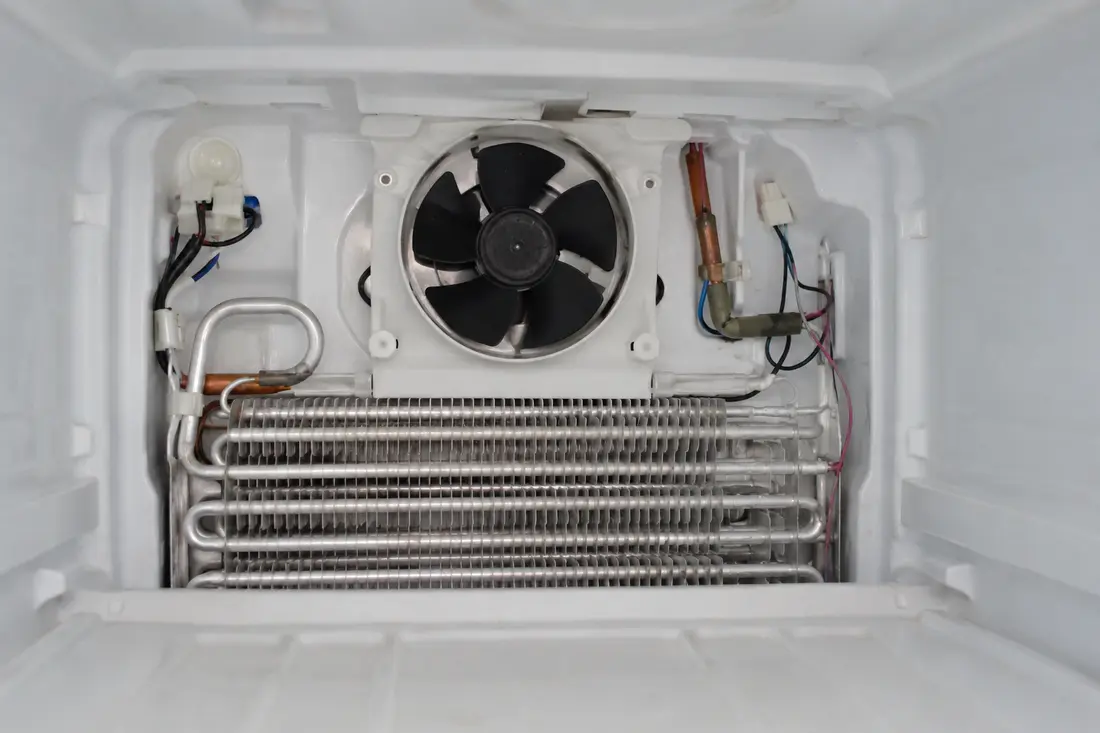 Refrigerator evaporator fan and coil behind the freezer panel
